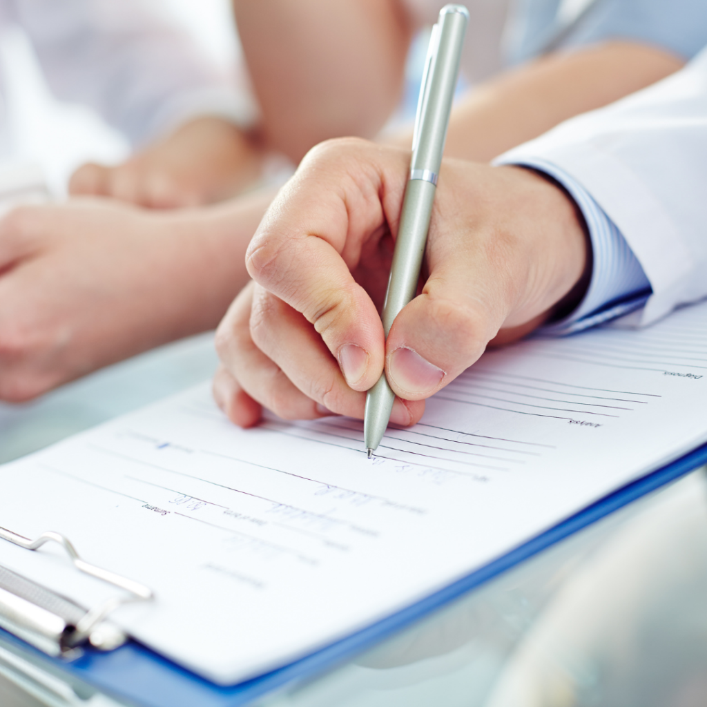 Image of a person holding a pen writing a prescription. This represents the beginning of Louise's grief, which started with a Lichen Sclerosus diagnosis.