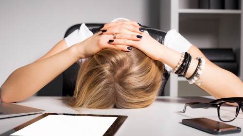 Person with their head on their desk, looking upset, representing the grief Megan felt.