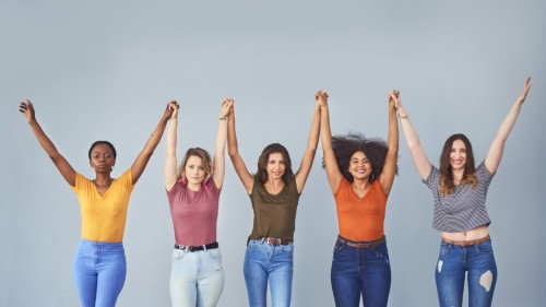 Image of 5 people in jeans and different colored t-shirts holding hands and raising their arms representing feeling empowered.